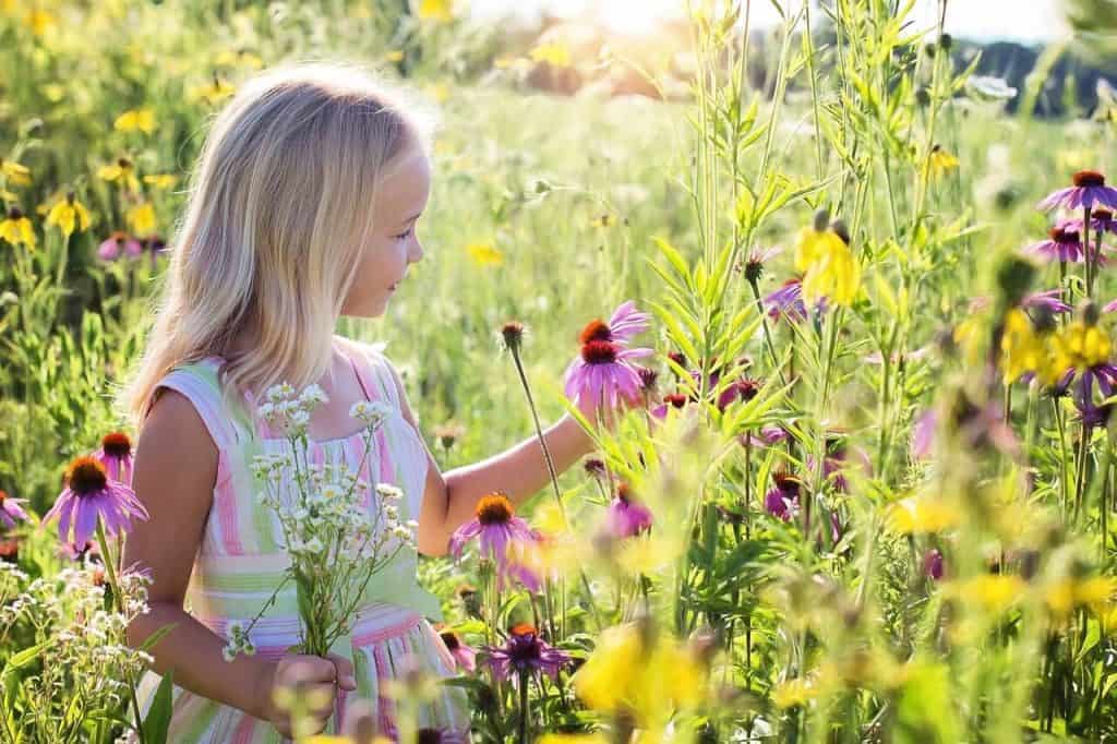 Petite fille dans un jardin luxuriant qui respect le calendrier des semis