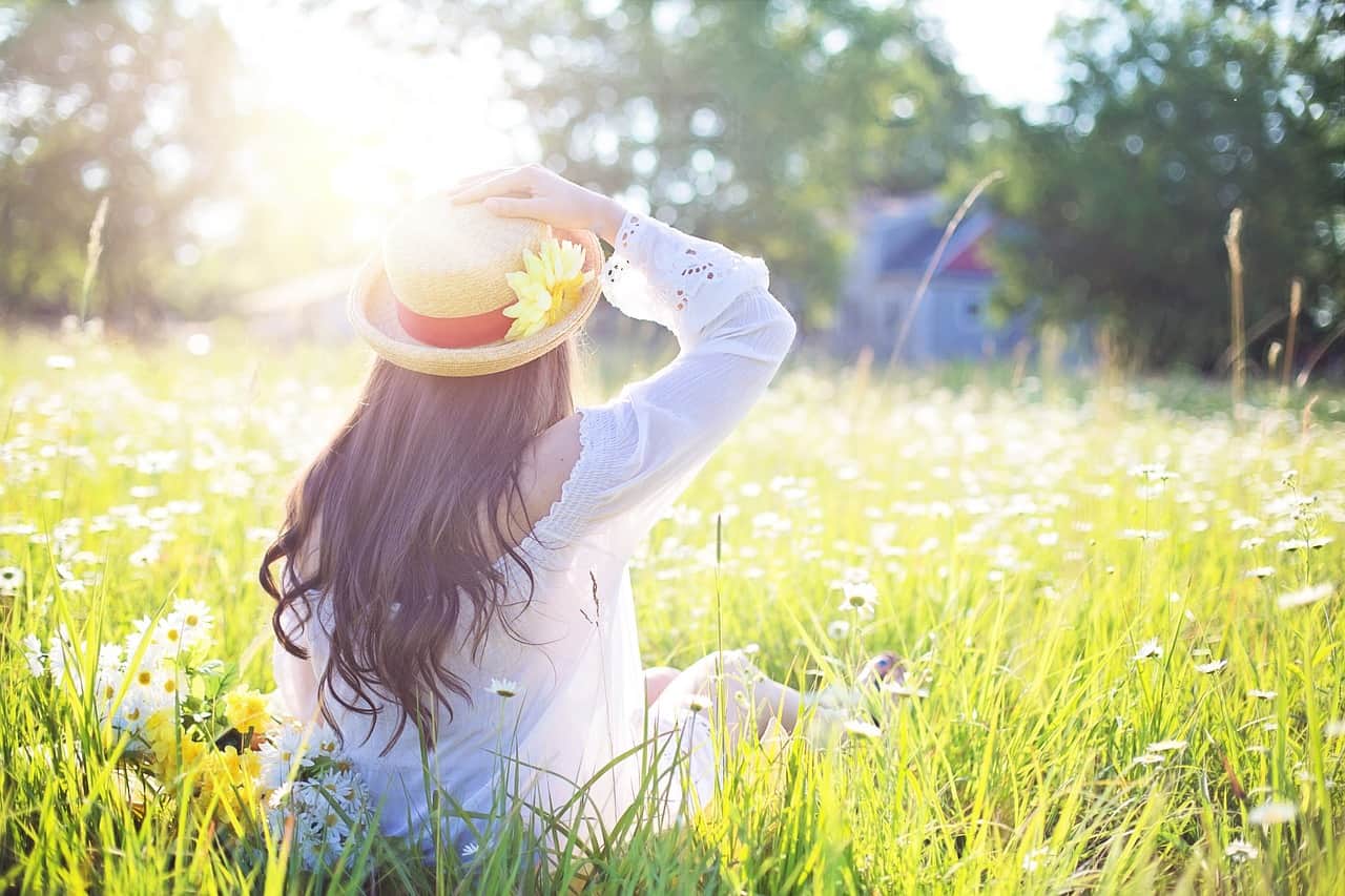 Femme dans un champ de fleurs, symbolisant l'harmonie entre l'humain et la nature, chère aux phytothérapeutes, naturopathes et herboristes.