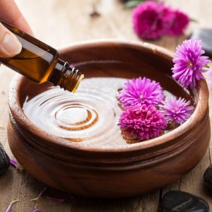 Une bouteille d'huile essentielle accompagnée d'une fleur, illustrant la formation en aromathérapie familiale